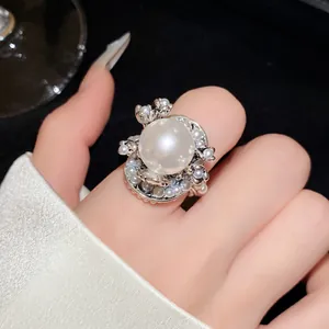 Detailansicht eines eleganten Silberrings mit einer großen Perle und floralem Perlendesign.