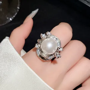 Detailansicht eines silbernen Blumenrings mit einer großen, glänzenden weißen Perle