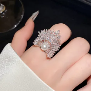 Nahaufnahme eines fächerförmigen Kristallrings mit Perle am Finger, eleganter Schmuck.