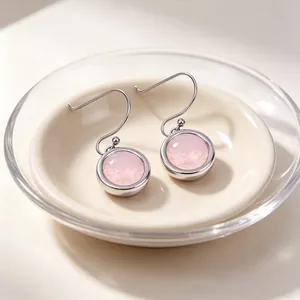 Close-up of elegant stainless steel drop earrings featuring a round pink cubic zirconia.