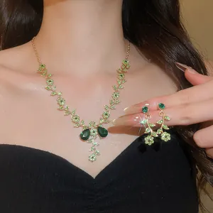 Parure de bijoux de mariée élégante avec cristaux verts, collier de fleurs et boucles.