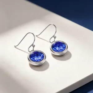 Close-up detail of silver stainless steel earrings with round blue faceted zircon stones