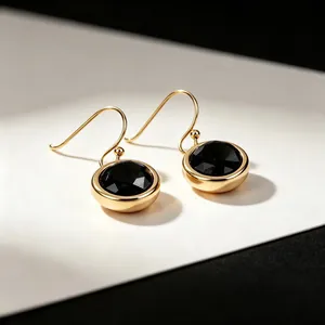 Close-up of elegant gold-plated drop earrings featuring faceted round black gemstones