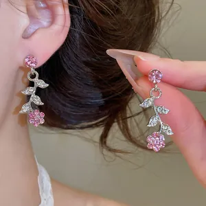 Vue détaillée exquise de boucles d'oreilles fleur rose avec des strass et feuilles chic