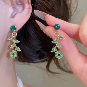 Gros plan détaillé des boucles d'oreilles vignes de fleurs en cristal vert étincelantes