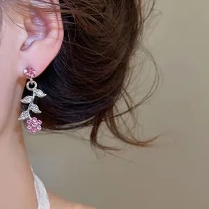 Gros plan de boucles d'oreilles fleurs en cristal rose avec détails de feuilles étincelantes.