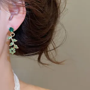 Détail de la boucle d'oreille vigne dorée avec strass verts et pendentif fleur