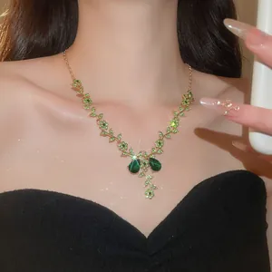Vue détaillée du collier doré aux motifs floraux verts et feuilles avec gemmes