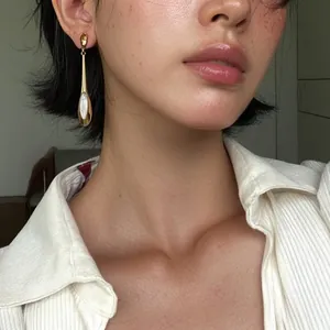 Boucles d'oreilles pendantes œil de chat minimalistes portées par un mannequin chic