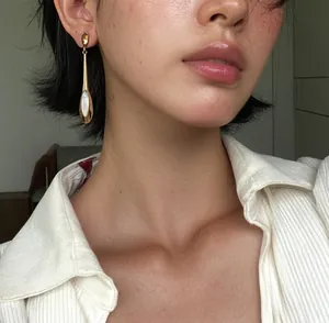 Gros plan de boucles d'oreilles pendantes dorées avec pierre œil de chat sur mannequin.