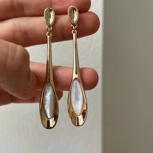Vue détaillée de boucles d'oreilles pendantes dorées avec pierre d'œil de chat