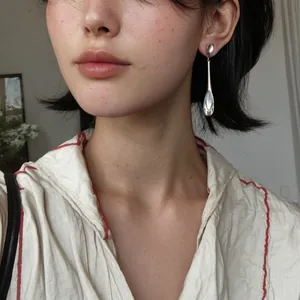 Détail de boucles d'oreilles minimalistes en argent avec pendentif œil-de-chat sur modèle