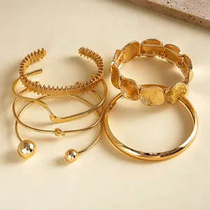 Gedetailleerd overzicht van zesdelige gouden geometrische armbandset met plooitexturen.