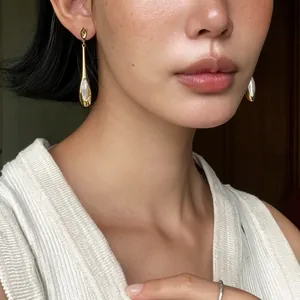 Détail de boucles d'oreilles pendantes dorées avec pierre œil de chat sur un mannequin