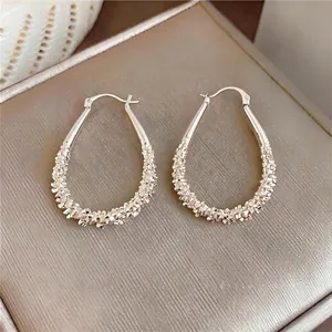 Close-up macro view of silver teardrop hoop earrings with a shimmering textured finish