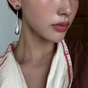 Vue rapprochée d'une boucle d'oreille pendante minimaliste en argent sur un mannequin.