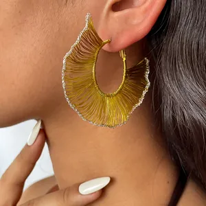Gros plan détaillé de boucles d'oreilles créoles tissées dorées avec bordure argentée.