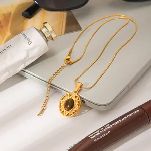 Close-up of vintage gold sunburst medallion necklace with natural stone pendant on a desk.