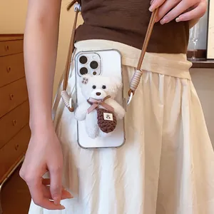 Detailed view of white plush bear accessory on transparent phone case with brown strap.