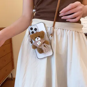 Detail of a crossbody plush bear phone case worn by a model in a cozy indoor setting
