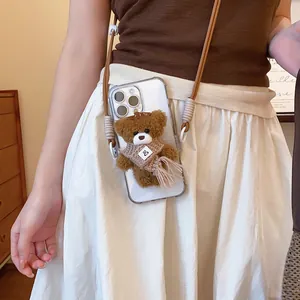 Detailed view of plush teddy bear charm on a clear phone case with shoulder strap