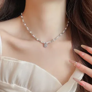 Close-up of a sparkling zircon pendant on a pearl necklace worn by a model