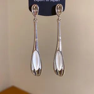 Nahaufnahme von eleganten Katzenaugen-Ohrringen in Tropfenform aus minimalistischem Silber