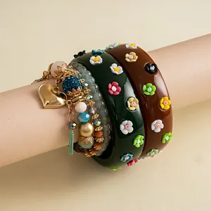 Detail of retro resin bangles with flowers and beaded charm bracelet with golden heart