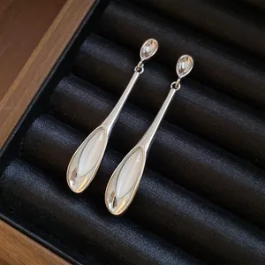 Elegante silberne Hängeohrringe mit weißen Katzenaugenstein-Anhängern auf Samt