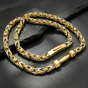 Makro-Detail einer goldenen Edelstahl-Byzantinerkette mit einem Hantel-Accessoire