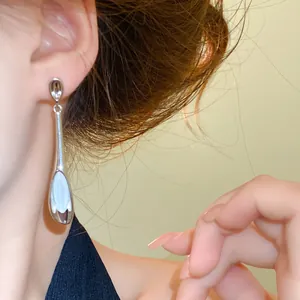 Detailansicht silberner Ohrhänger mit Katzenauge-Stein am Modellohr, minimalistisch
