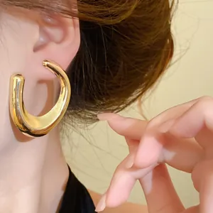 Gedetailleerde close-up van een stijlvolle gouden dikke C-vormige oorbel aan het oor van model