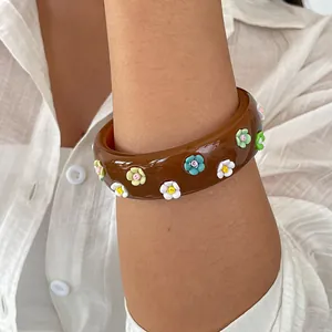 Close-up of a vintage brown resin bangle featuring colorful 3D flower charms