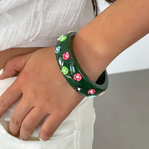 Detailed view of retro dark green resin bangle with colorful small flower decorations on arm