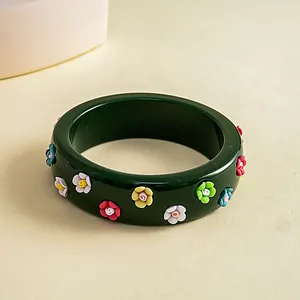 Detailed view of a dark green resin bangle featuring small colorful 3D flower accents.