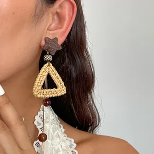 Detailed view of bohemian rattan woven triangle earrings with retro star and tassel