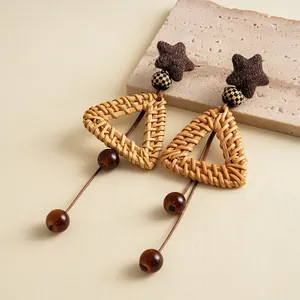 Detail of vintage rattan earrings with triangular woven design and brown glass tassels