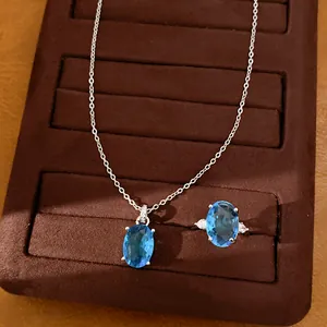 Close-up detail of silver necklace and ring set with oval blue gemstones in a box