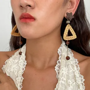 Close-up of retro woven triangle tassel earrings worn by model with lace top.