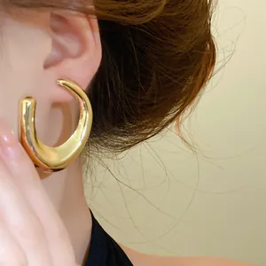 Detailweergave van goudkleurige holle oorringen met een minimalistisch ontwerp