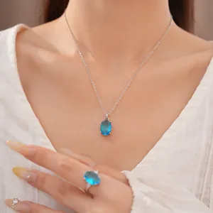 Elegant oval blue zircon pendant necklace and matching ring set shown on female model