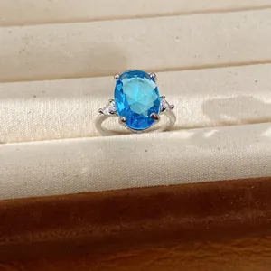 Detail of an oval-cut blue zircon ring in a silver-toned setting and jewelry box