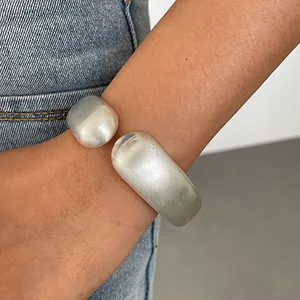 Close-up of a silver-toned chunky open cuff bracelet with textured wrinkled finish