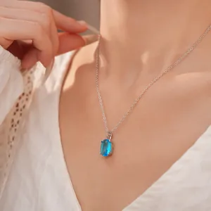 Close-up of an elegant silver chain necklace featuring an oval blue zircon stone