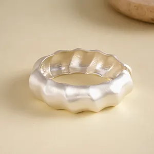 Close-up of a silver metallic pleated wavy textured bangle with a geometric design.