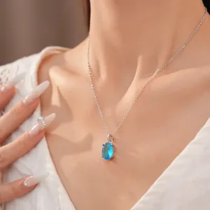 Elegant silver necklace featuring a vivid blue oval zircon pendant on a model