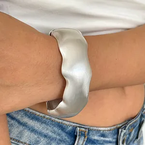 Elegant close-up shot of a wide silver pleated metal cuff bracelet with wavy texture
