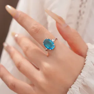 Detailed close-up of an elegant silver ring with a large oval blue zircon gemstone