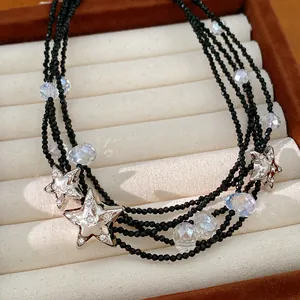 Detailopname van een gelaagde zwarte kralenketting met fonkelende kristallen sterren.