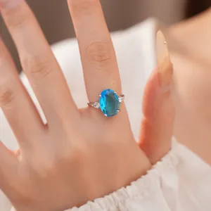 Macro view of an elegant oval blue zircon ring with silver-tone band on a model's hand